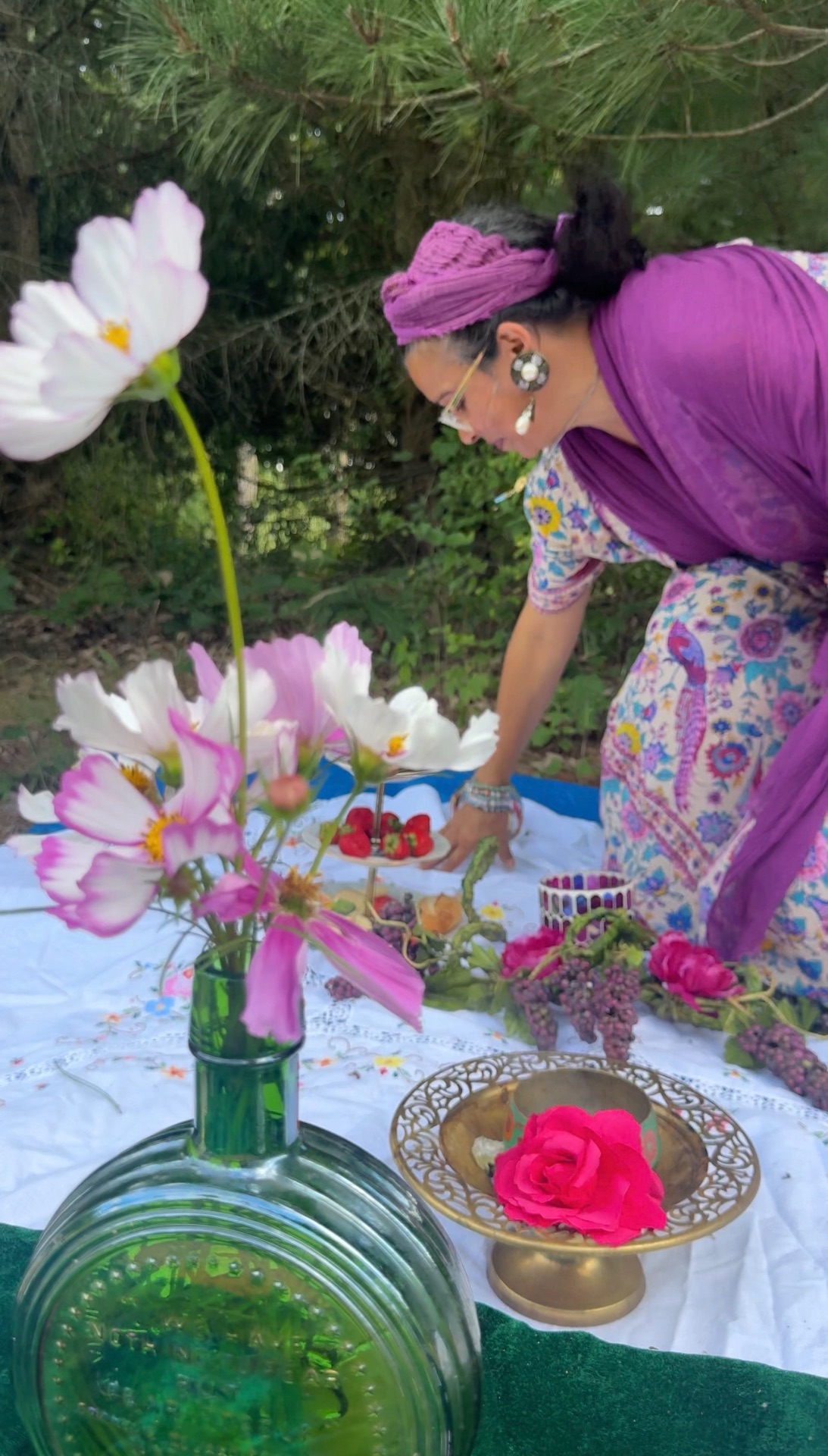 Mariela arranging an outdoor offering of cosmos flowers and fruit